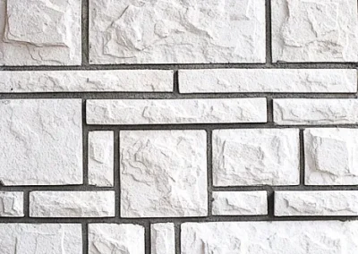White textured stone wall with rectangular and square tiles in a geometric pattern.