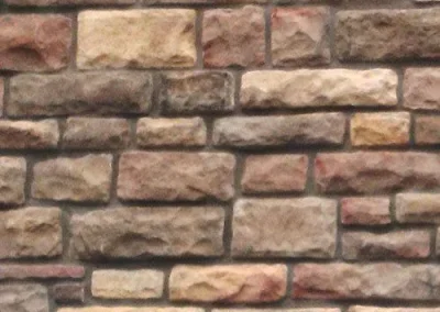 A close-up view of a brick wall made of unevenly sized and colored rectangular stones.