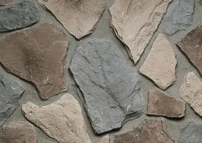 Tan and gray irregular stone wall with visible mortar between the stones.