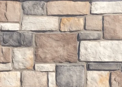 A wall made of rectangular stones in beige, gray, and white, arranged in a staggered pattern.