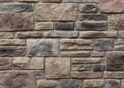 A textured stone wall with rectangular, unevenly sized stones in shades of gray, tan, and brown.