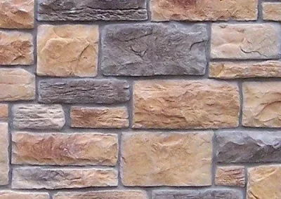 Rectangular tan and gray stones arranged in a brick-like pattern to form a decorative wall surface.