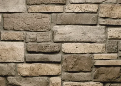 A close-up of a stone brick wall with various shades of beige and gray rectangular stones.