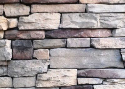 Close-up of a textured stone wall with unevenly stacked rectangular stones in various shades of gray and brown.