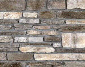 Mountain Ledge – Northern Creme A close-up of a stone wall with rectangular, textured stones in various shades of gray and beige.