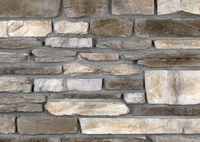 A close-up of a stone wall with rectangular, textured stones in various shades of gray and beige.