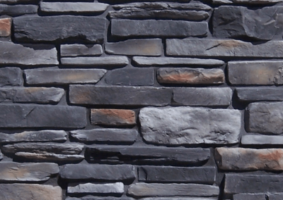 Gray stone brick wall with variously sized and shaped stones, some with light brownish highlights.