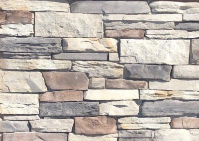 A close-up of a wall made of rectangular, stacked stone bricks in various shades of gray and beige.