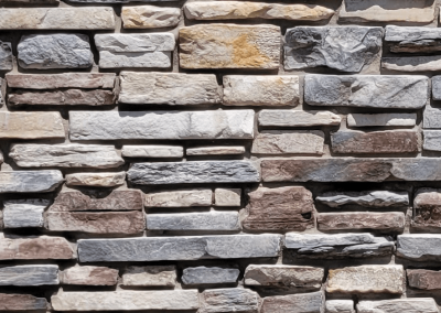 A close-up of a textured stone wall with variously sized and colored rectangular stones.