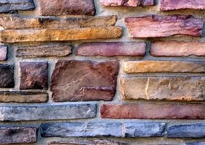 A close-up of a multicolored stone wall with irregularly shaped stones and visible mortar lines.