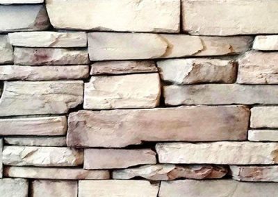 Light tan and beige rectangular stone bricks stacked in a rough, uneven pattern.
