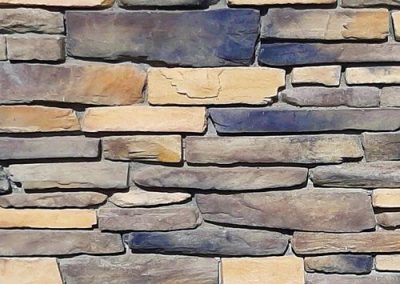 A wall made of stacked rectangular stones in shades of beige, tan, and gray.