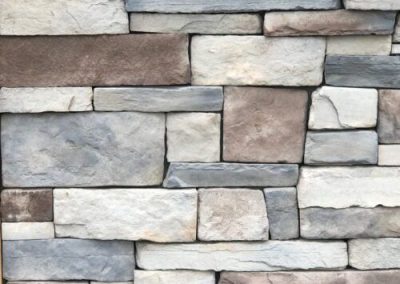 A close-up of a wall made of rectangular, multicolored stone bricks arranged in a staggered pattern.