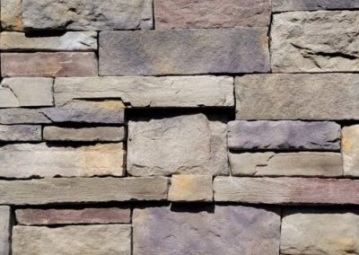 Close-up of a stone wall with variously sized rectangular stones in earthy tones arranged in a pattern.