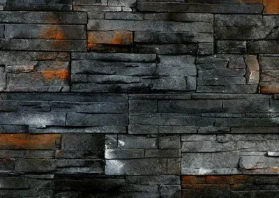 Dark stone wall with horizontal stacked slabs, featuring black, gray, and rusty orange patches.