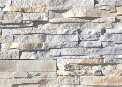 Stacked stone wall with horizontal layers of rectangular, light-colored stones and rough textures.