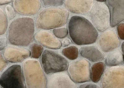 A close-up of a stone wall with variously sized and colored smooth rocks set in mortar.