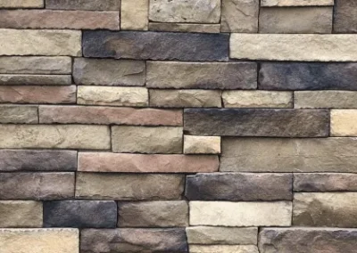 A close-up of a wall made of rectangular, multi-colored stone bricks arranged in a staggered pattern.