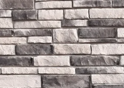 Gray and white rectangular stone bricks arranged in a horizontal, staggered pattern on a wall.