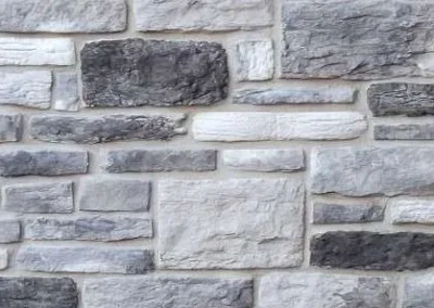 Gray stone wall with rectangular stones of varying sizes, arranged in a horizontal pattern.