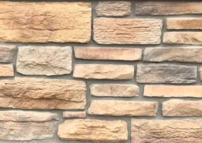 Tan and gray rectangular stone bricks arranged in a horizontal pattern on a wall.