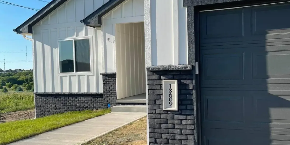 Modern house exterior with white siding, black brick, and the address number 18609 displayed by the garage.