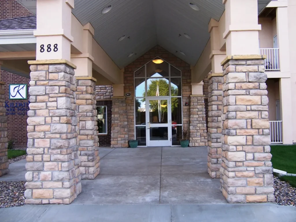 Stone entryway with pillars leads to glass doors of a building; address number 888 visible on a column.