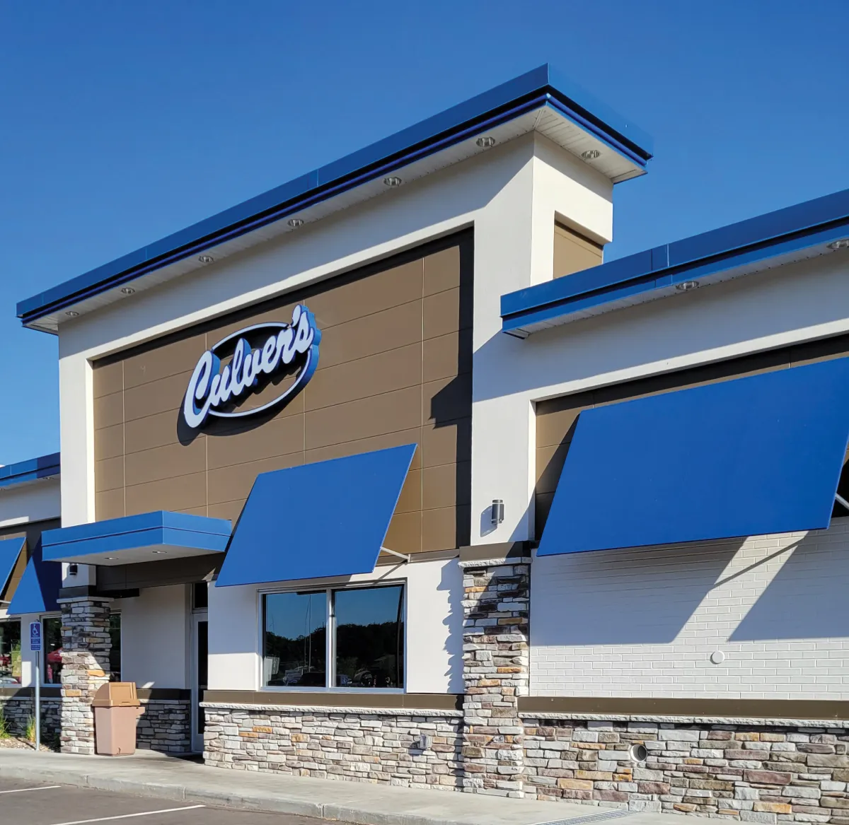Culver’s restaurant exterior with blue awnings, stone accents, and a clear blue sky.