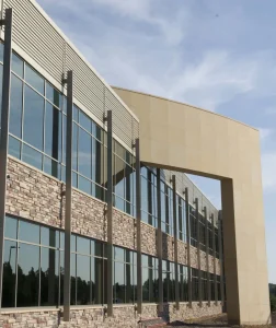 commercial-5 Modern building with large glass windows, stone accents, and a tall arched entryway under a blue sky.