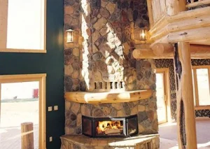 fireplace-10 Stone fireplace with a roaring fire in a rustic log cabin living room with large windows.