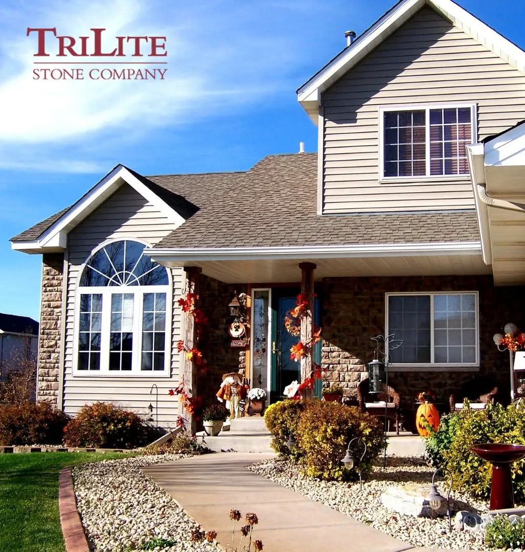 Tan house with stone accents and fall decorations, with "TriLite Stone Company" logo in the top left corner.