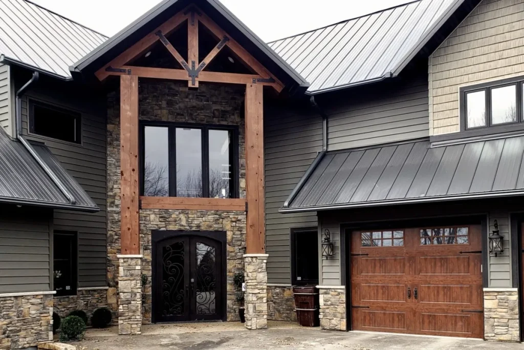 Modern house with stone accents, wooden garage door, large windows, and metal roof.