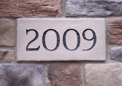 A stone plaque with the engraved number “2009” set in a brick wall.