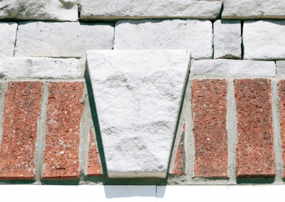 Red bricks and white stones with a central white keystone on a building facade.
