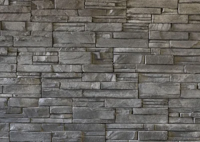 Gray stacked stone wall with rectangular stones arranged in a staggered, brick-like pattern.