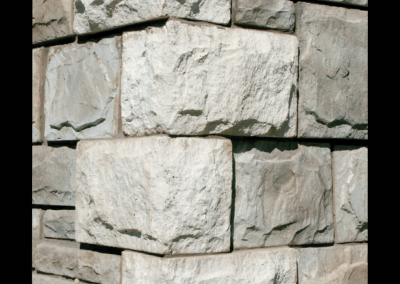 Corner of a stone wall with large rectangular blocks, shown against a black background.
