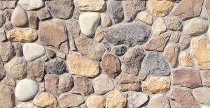 A close-up of a stone wall with variously sized and colored rocks set in mortar.