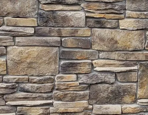 Californial-Blend-Carmel A close-up view of a rustic stone wall with various sizes and shades of rectangular stones.