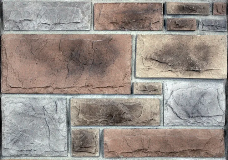 Castlerock-Buckskin Rectangular stone wall with various sized bricks in shades of brown, gray, and beige with visible textures.