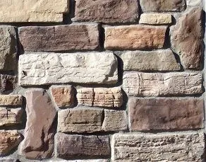 A close-up of a stone wall with rectangular, multi-colored bricks stacked in a horizontal pattern.
