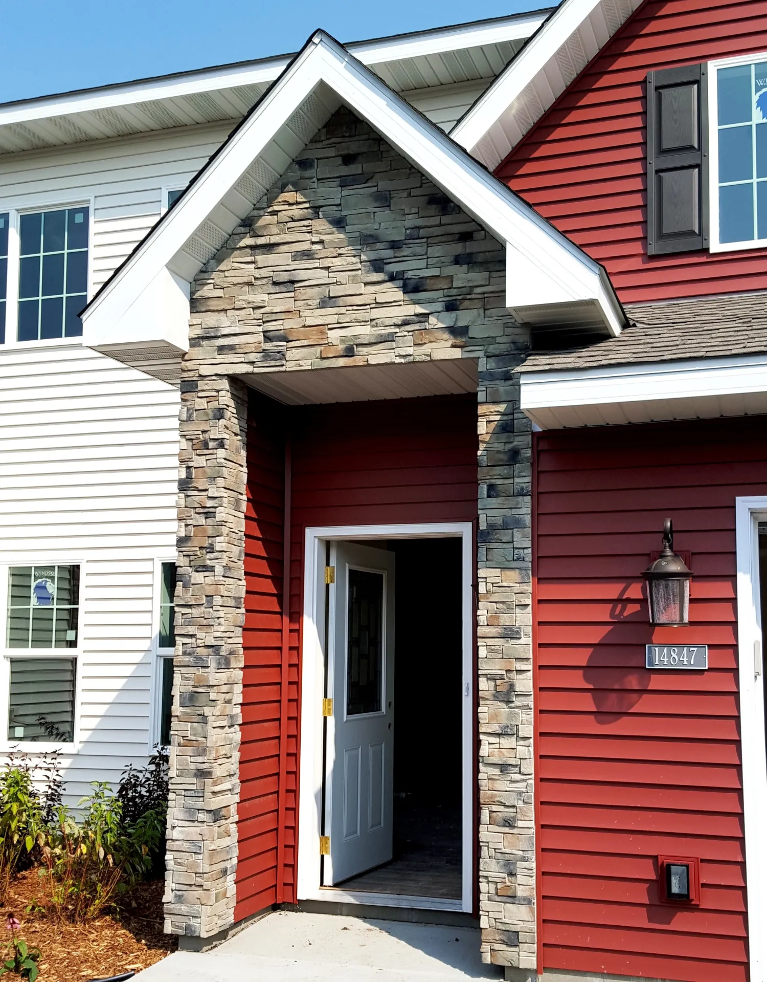 Red and white house with stone entryway, open front door, windows, and house number 14847.