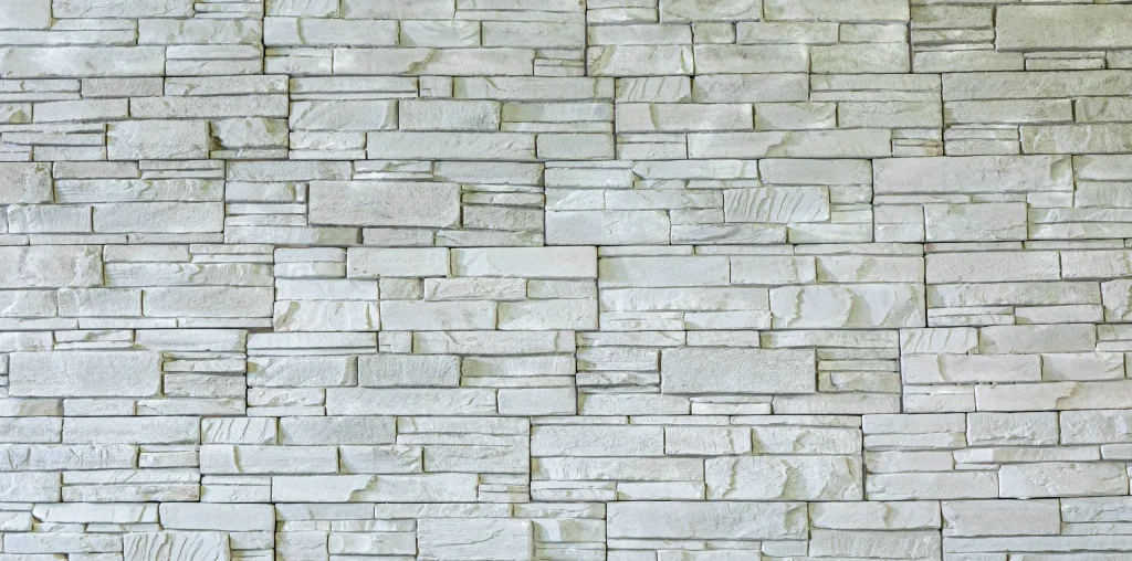 Light gray stone wall with rectangular and square blocks arranged in a horizontal, staggered pattern.