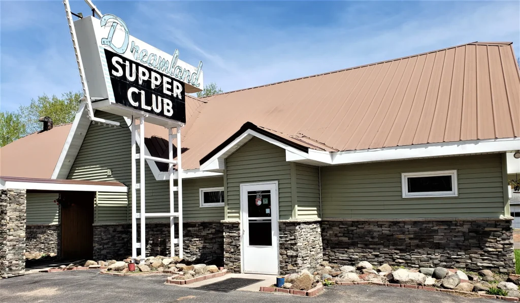 A building with a metal roof and a sign reading “Dreamland Supper Club” above the entrance.