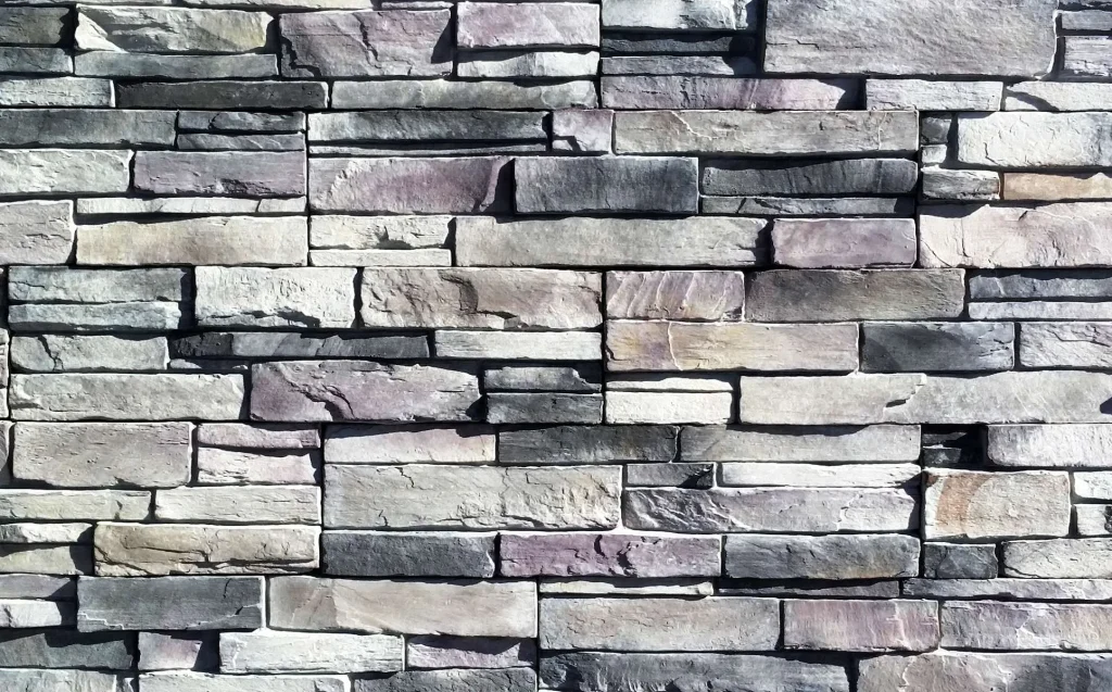 Gray stone brick wall with uneven rectangular stones stacked in a horizontal pattern.