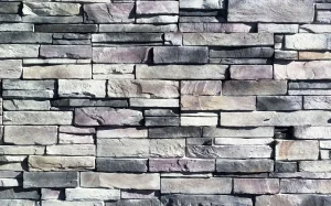Gray stone brick wall with uneven rectangular stones stacked in a horizontal pattern.