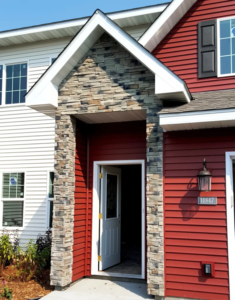 Red house with stone entryway, open white door, windows, and address plaque reading 14847.