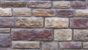 A close-up of a brick wall with various shades of beige and purple stones arranged in a pattern.