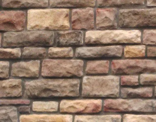 European-Limestone-Caspian_Centra A close-up of a textured stone brick wall with various sizes and shades of tan, brown, and gray bricks.