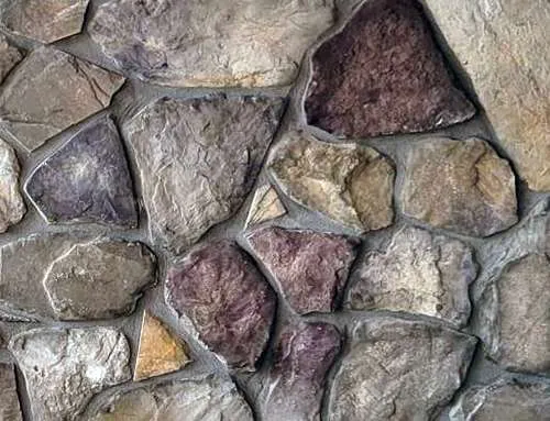 Fieldstone-Bucks-County A close-up of a stone wall with irregularly shaped, multicolored stones and visible mortar.
