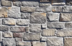 A close-up of a stone wall with variously sized rectangular gray and tan stones.